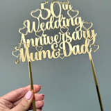 Load image into Gallery viewer, Gold acrylic cake topper with the words '50th Wedding Anniversary Mum & Dad' surrounded by hearts, designed for a golden anniversary celebration.