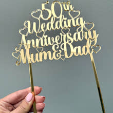 Load image into Gallery viewer, Gold acrylic cake topper with the words '50th Wedding Anniversary Mum & Dad' surrounded by hearts, designed for a golden anniversary celebration.