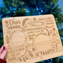 Load image into Gallery viewer, Wooden Christmas platter with engraved text in front of a decorated Christmas tree.