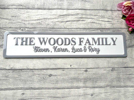 Family nameplate with 'The Woods Family' on a wooden surface with flowers.
