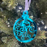 Load image into Gallery viewer, A blue mirrored acrylic Christmas tree decoration with the text 'BMX' and a star cut-out, hanging from a tree with lights and green needles in the background.
