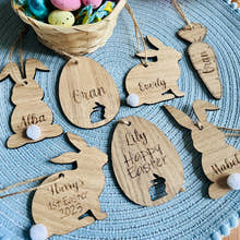 Load image into Gallery viewer, A set of seven wooden hanging Easter decorations, including bunny shapes and an egg design, with personalized engravings of names.