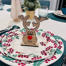 Load image into Gallery viewer, Wooden reindeer place name holder with red nose and engraved name “Mum” on a festive Christmas dinner table with holly plates and holiday decorations.