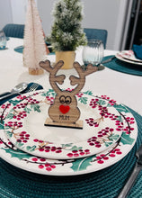 Load image into Gallery viewer, Wooden reindeer place name holder with red nose and engraved name “Mum” on a festive Christmas dinner table with holly plates and holiday decorations.