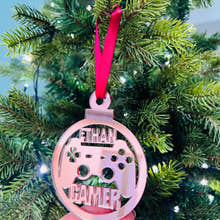 Load image into Gallery viewer, A hand holding a pink Christmas tree decoration with 'Gamer' text and a game controller shape.
