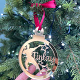 Load image into Gallery viewer, A gold-colored Christmas tree decoration featuring the silhouette of a boy in a karate stance, with a red bow on top and a hand holding it against a blurred green Christmas tree background. The hand has a glittery finish.