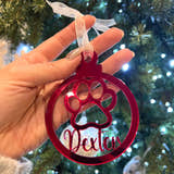 Load image into Gallery viewer, A hand holding a red Christmas tree decoration with a paw print design and the name 'Dexter' written on it.