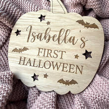 Load image into Gallery viewer, Wooden pumpkin-shaped plaque with 'Isabella's First Halloween' text on a textured fabric background
