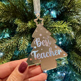 Load image into Gallery viewer, Decorative ornament with 'Best Teacher' text held in front of a Christmas tree.