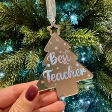 Load image into Gallery viewer, Decorative ornament with 'Best Teacher' text held in front of a Christmas tree.