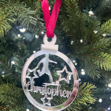 Load image into Gallery viewer, A silver-colored Christmas tree decoration featuring the name 'Christopher' laser cut and engraved on a round mirrored acrylic ornament, with a red ribbon hanging from the top.