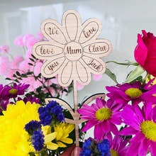 Load image into Gallery viewer, A freestanding wooden flower-shaped card with personalized message, placed amidst vibrant flowers.