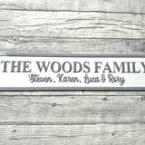 Load image into Gallery viewer, Family name plaque on a wooden surface with flowers in the corner