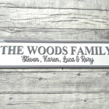 Load image into Gallery viewer, Family name plaque on a wooden surface with flowers in the corner
