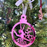 Load image into Gallery viewer, A pink circular Christmas tree decoration with a gymnast figure in the center, hanging on a Christmas tree.