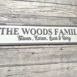 Load image into Gallery viewer, Family name plaque on a wooden surface with flowers in the corner