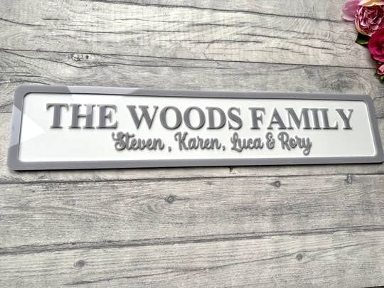 Family name plaque on a wooden surface with flowers in the corner