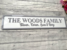 Load image into Gallery viewer, Family name plaque on a wooden surface with flowers in the corner