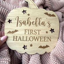 Load image into Gallery viewer, Wooden pumpkin-shaped plaque with 'Isabella's First Halloween' text on a textured fabric background