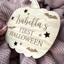 Load image into Gallery viewer, Wooden pumpkin-shaped ornament with 'Isabella's First Halloween' text on a textured fabric background