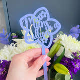 Load image into Gallery viewer, A hand holding a pink acrylic flower insert with the words 'Mum you billion' cut out of it, set against the backdrop of a bouquet of purple and white flowers.