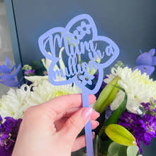 Load image into Gallery viewer, A hand holding a pink acrylic flower insert with the words 'Mum you billion' cut out of it, set against the backdrop of a bouquet of purple and white flowers.