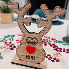 Load image into Gallery viewer, Wooden reindeer place name holder with red nose and engraved name “Mum” on a festive Christmas dinner table with holly plates and holiday decorations.