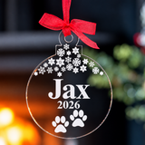 Load image into Gallery viewer, Personalised dog Christmas bauble featuring the name Jax, 2026, paw prints and snowflakes on clear acrylic with a red ribbon