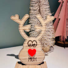 Load image into Gallery viewer, Wooden reindeer place name holder with red nose and engraved name “Mum” on a festive Christmas dinner table with holly plates and holiday decorations.