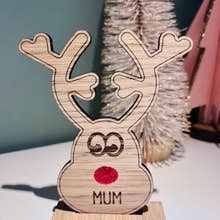 Load image into Gallery viewer, Wooden reindeer place name holder with red nose and engraved name “Mum” on a festive Christmas dinner table with holly plates and holiday decorations.