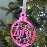 Load image into Gallery viewer, A pink, star-shaped Christmas tree decoration with the word 'Zara' engraved in the center, hanging from a tree with lights and greenery in the background.