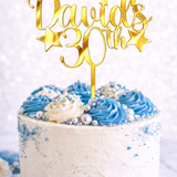Load image into Gallery viewer, Personalised gold mirror acrylic birthday cake topper with custom name and age on white celebration cake with blue buttercream and silver decorations.