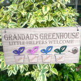 Load image into Gallery viewer, Personalised Grandad’s Greenhouse wooden sign with little helpers welcome text with 4 plant pot design hanging in a sunny garden