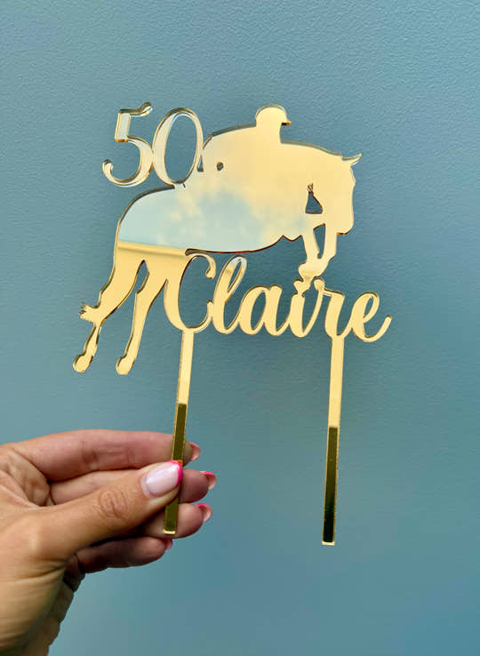 Close-up of personalised gold mirror acrylic horse cake topper featuring a horse rider silhouette, name and age.