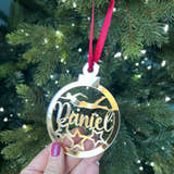 Load image into Gallery viewer, A hand holding a gold-colored Christmas tree decoration with the name 'Daniel' engraved on it, against a blurred background of a Christmas tree with lights.