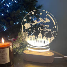 Load image into Gallery viewer, A clear acrylic snowglobe with a 'Merry Christmas' message, illuminated from within, placed on a table with a blurred Christmas tree and gifts in the background.