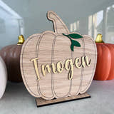 Load image into Gallery viewer, A wooden pumpkin-shaped decoration with 'Ingen' printed in metallic gold lettering, positioned on a stand.