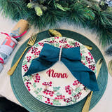 Load image into Gallery viewer, Christmas dinner table setting with personalised acrylic place name ‘Nana’ in red, festive plate and green napkin