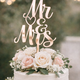 Load image into Gallery viewer, Rose Gold mirror acrylic Mr and Mrs wedding cake topper on a white buttercream wedding cake with blush roses and greenery.
