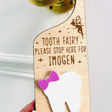 Load image into Gallery viewer, Personalised wooden Tooth Fairy door hanger with engraved text and white tooth shape with purple bow, hanging on a brass doorknob