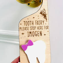 Load image into Gallery viewer, Personalised wooden Tooth Fairy door hanger with engraved text and white tooth shape with purple bow, hanging on a brass doorknob