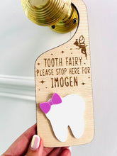 Load image into Gallery viewer, Personalised wooden Tooth Fairy door hanger with engraved text and white tooth shape with purple bow, hanging on a brass doorknob