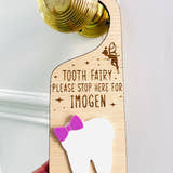 Load image into Gallery viewer, Personalised wooden Tooth Fairy door hanger with engraved text and white tooth shape with purple bow, hanging on a brass doorknob