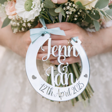 Load image into Gallery viewer, Bride holding pastel pink and cream wedding bouquet with personalised silver mirror horseshoe engraved Jenn & Ian 12th April 2025