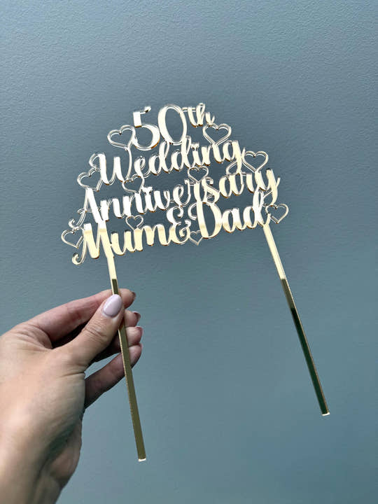 Personalised gold mirror acrylic 50th Wedding Anniversary Mum & Dad cake topper held in a hand, showing its size