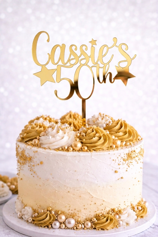 Personalised 50th birthday cake topper in gold mirror acrylic with star details, reading 'Name's 50th', on a white buttercream celebration cake.