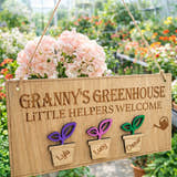 Load image into Gallery viewer, Personalised Grandad’s Greenhouse wooden sign with little helpers welcome text and Theo plant pot design hanging in a FLOWER illed greenhouse.