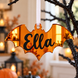 Load image into Gallery viewer, Personalised bat Halloween tree decoration in orange mirrored acrylic with the name in black
