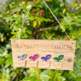 Load image into Gallery viewer, Personalised Grandad’s Greenhouse wooden sign with little helpers welcome text and plant pot design hanging in a GREEN GARDEN.
