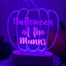 Load image into Gallery viewer, A personalised LED light up stand with a pumpkin shape, illuminated in purple and with the text 'HALLOWEEN AT THE MINNS' engraved on it.
